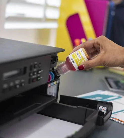 Brother refillable ink bottle being inserted into an ink tank printer